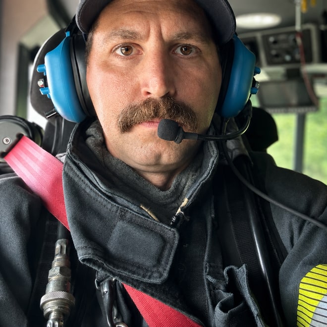 Alex Tarsha in turnout gear, riding in the cab